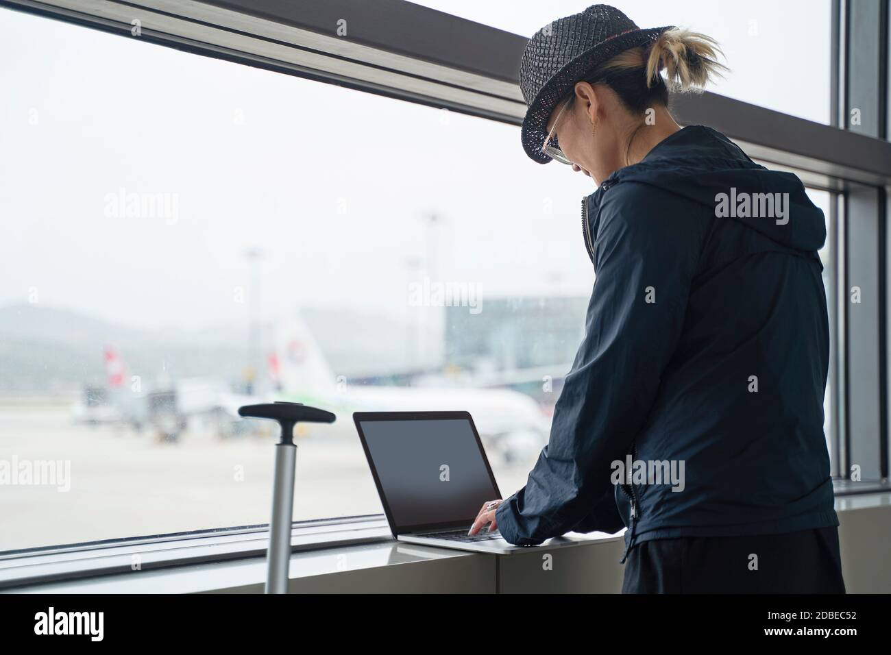 Junge asiatische Frau weibliche Flugreisende mit Laptop während der Wartezeit Für das Einsteigen in das Flughafenterminal Stockfoto