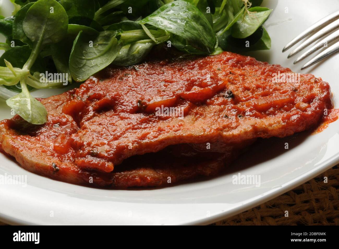 Schweinefilet mit Tomatensauce und Maissalat Stockfoto