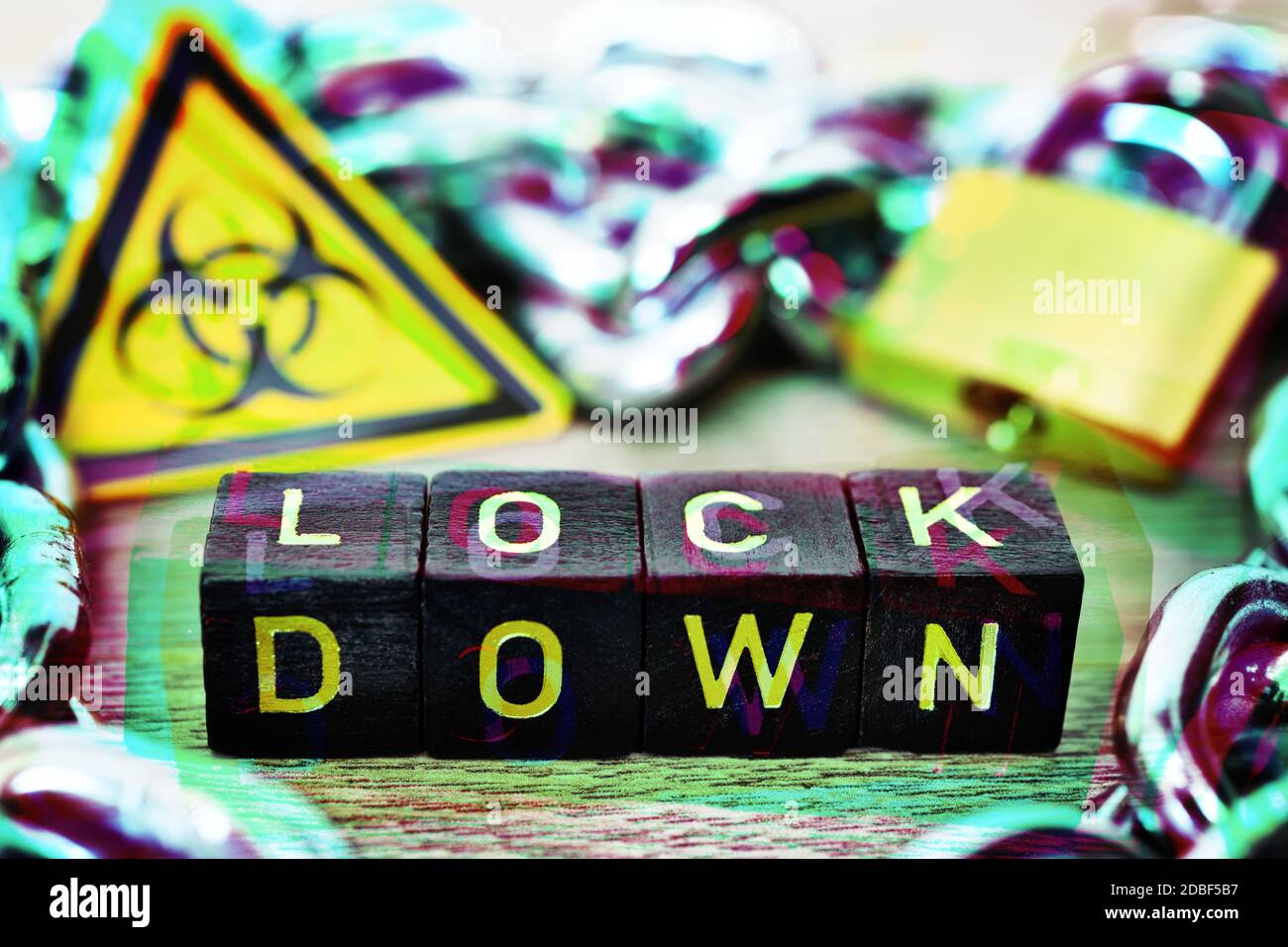 Buchstabenwürfel bilden das Wort Lockdown vor Biohazard Zeichen, Eisenkette und Vorhängeschloss, Corona Lockdown Stockfoto