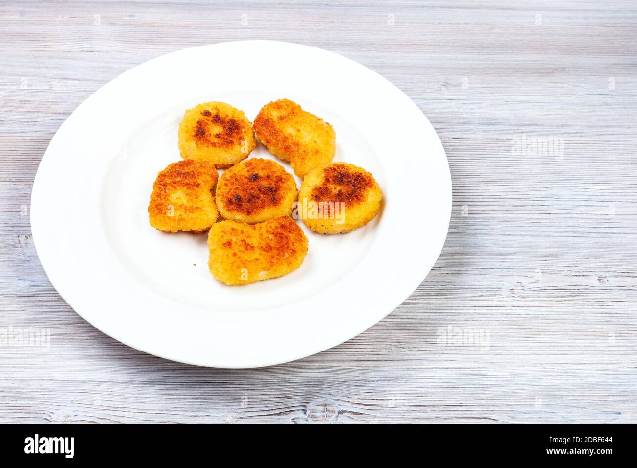 Portion gebratene Chicken Nuggets auf weißem Teller auf grauem Holzbrett Stockfoto