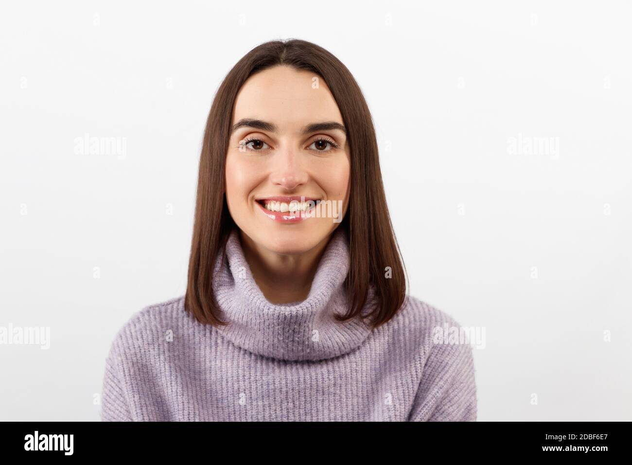 Charmante Mädchen in einem lila Pullover im Studio auf Ein weißer Hintergrund lächelt wunderschön und sehr glücklich Stockfoto