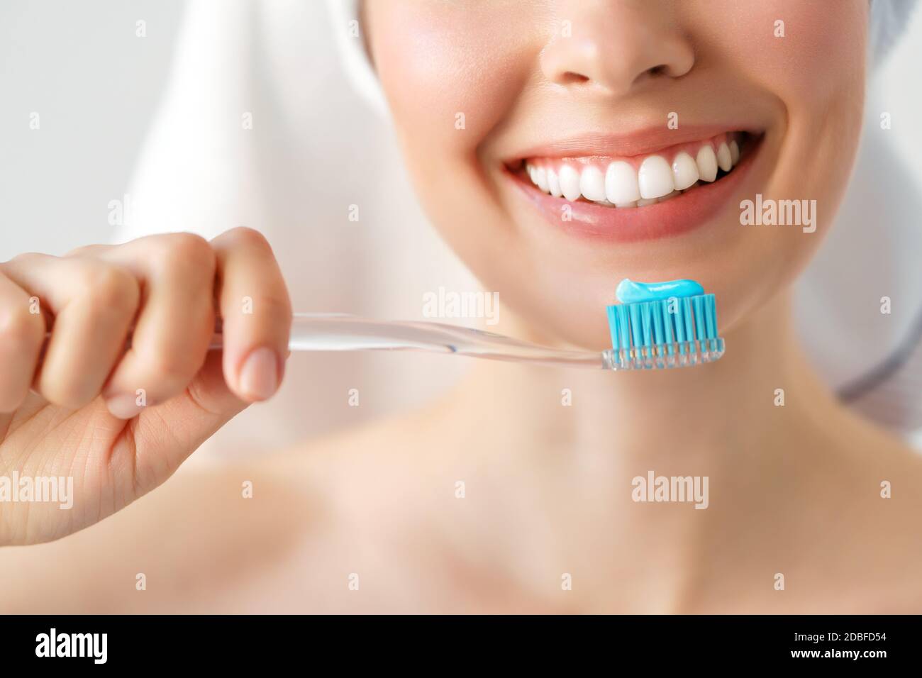 Lächelnde Frau, die ihre Zähne mit einer Zahnbürste in einem zahnhygienischen Konzept putzt. Isoliert auf Weiß Stockfoto