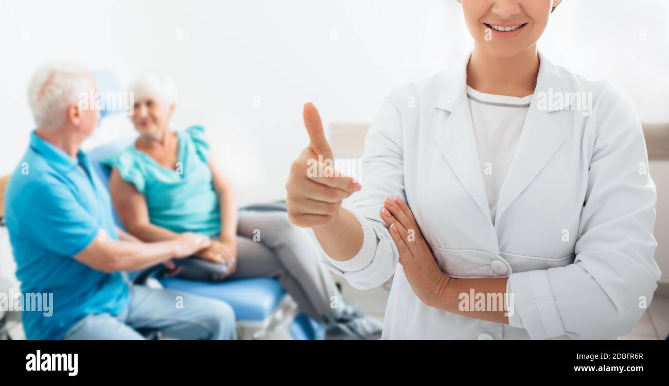 Lächelnd HNO-Arzt mit ihr älterer Patienten im Hintergrund, im Vordergrund der medizinischen Zimmer konzentrieren Stockfoto