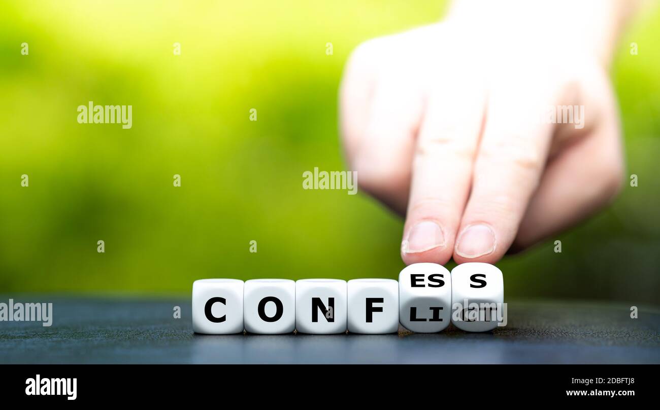 Hand dreht Würfel und ändert das Wort 'Konflikt' in 'Geständnis'. Stockfoto