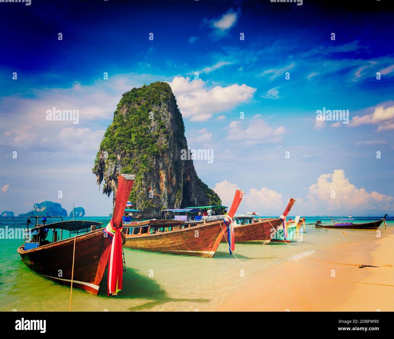 Vintage Retro-Effekt gefiltertes Hipster-Stil Reisebild von Long Tail Boot auf tropischen Strand mit Kalkstein Felsen, Krabi, Thailand Stockfoto