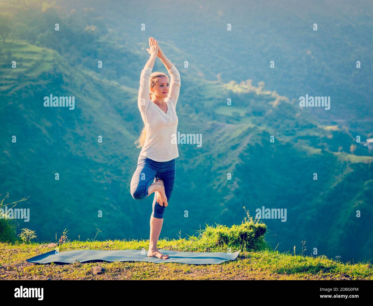 Vintage Retro-Effekt Hipster-Stil Bild der Frau Praktiken Balance Yoga Asana Vrikshasana Baum Pose in Himalaya Berge im Freien am Morgen. H Stockfoto