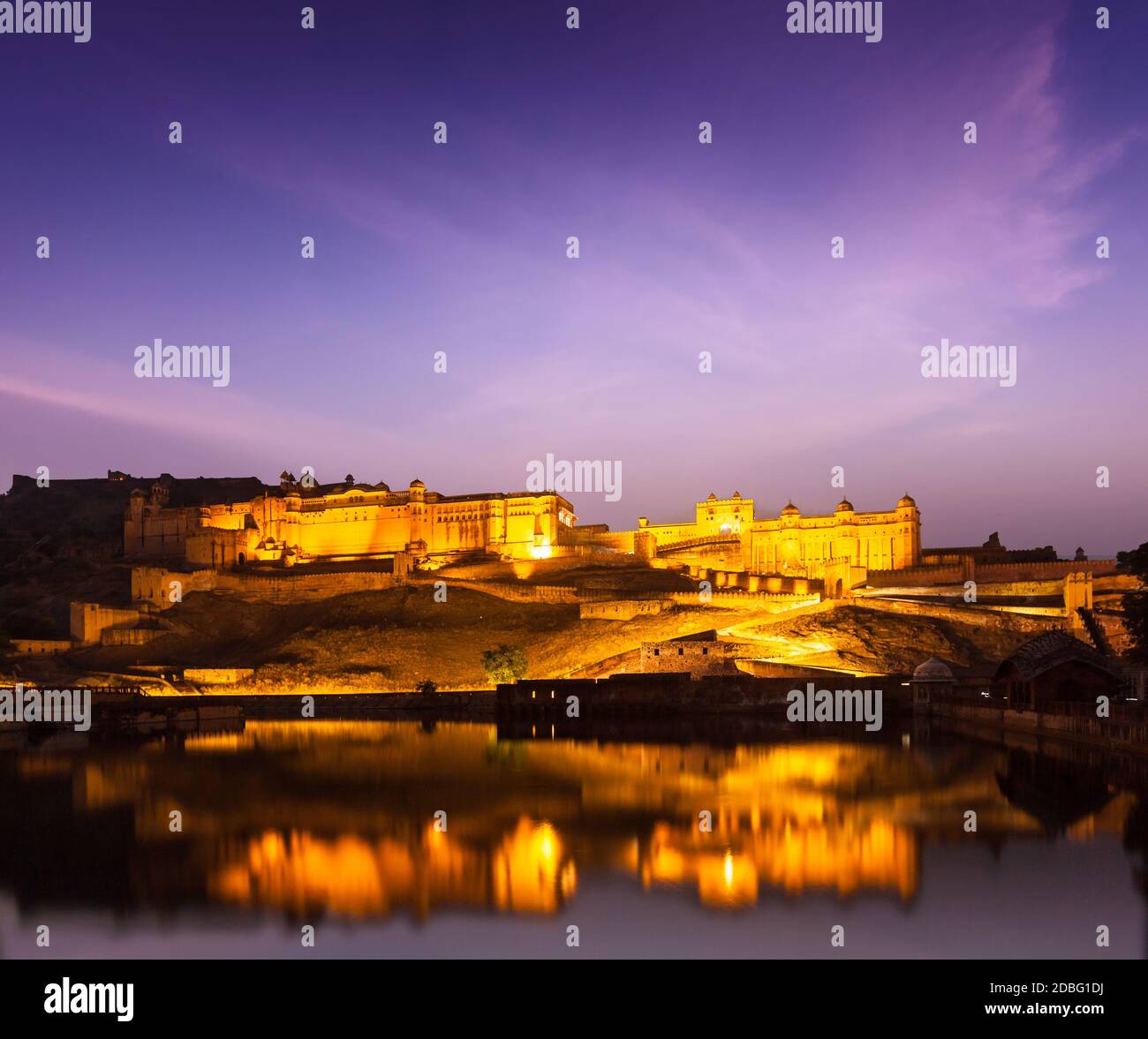 Amer Fort (Amber Fort) beleuchtet in der Nacht - eine der wichtigsten Sehenswürdigkeiten in Jaipur, Rajastan, Indien Refelcting in Maota See in der Dämmerung Stockfoto