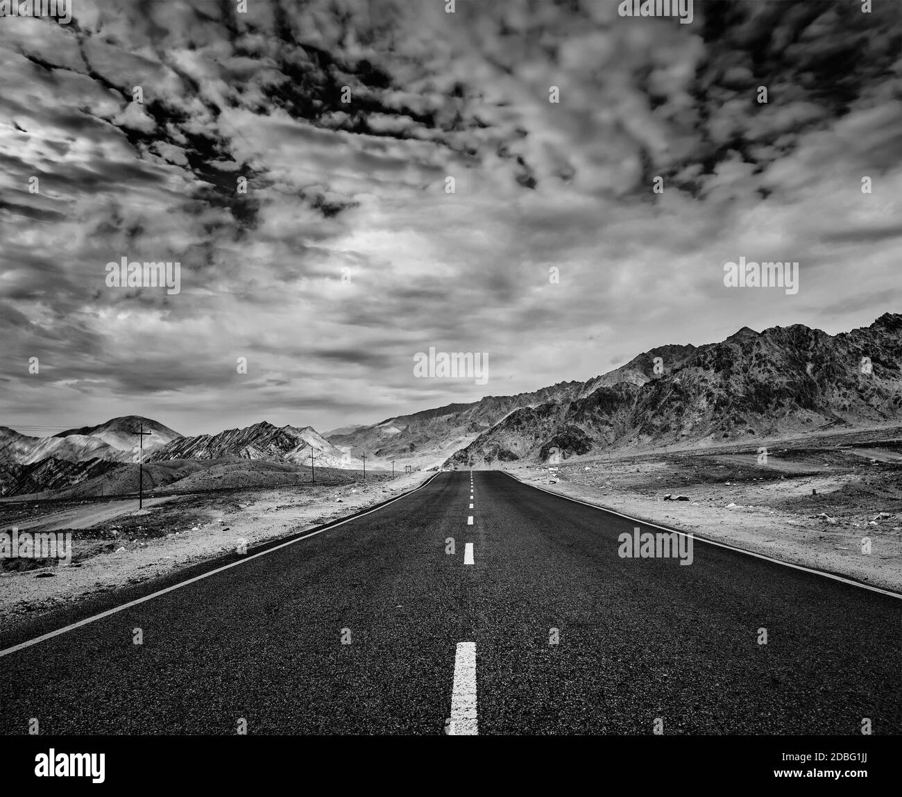 Reise vorwärts Konzept Hintergrund - Straße im Himalaya mit Bergen und dramatischen Wolken. Ladakh, Jammu und Kaschmir, Indien. Schwarz-Weiß-Version Stockfoto