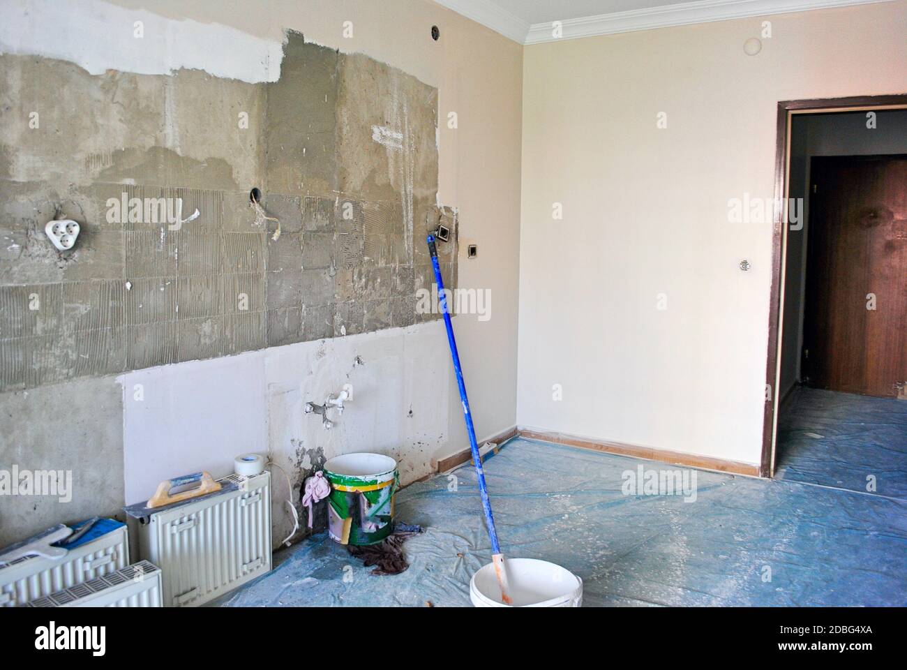 Teilweise bemalte Wohnung Küche Renovierung im Gange mit Eimern und Pinsel. Cremefarbene Betonwand. Stockfoto