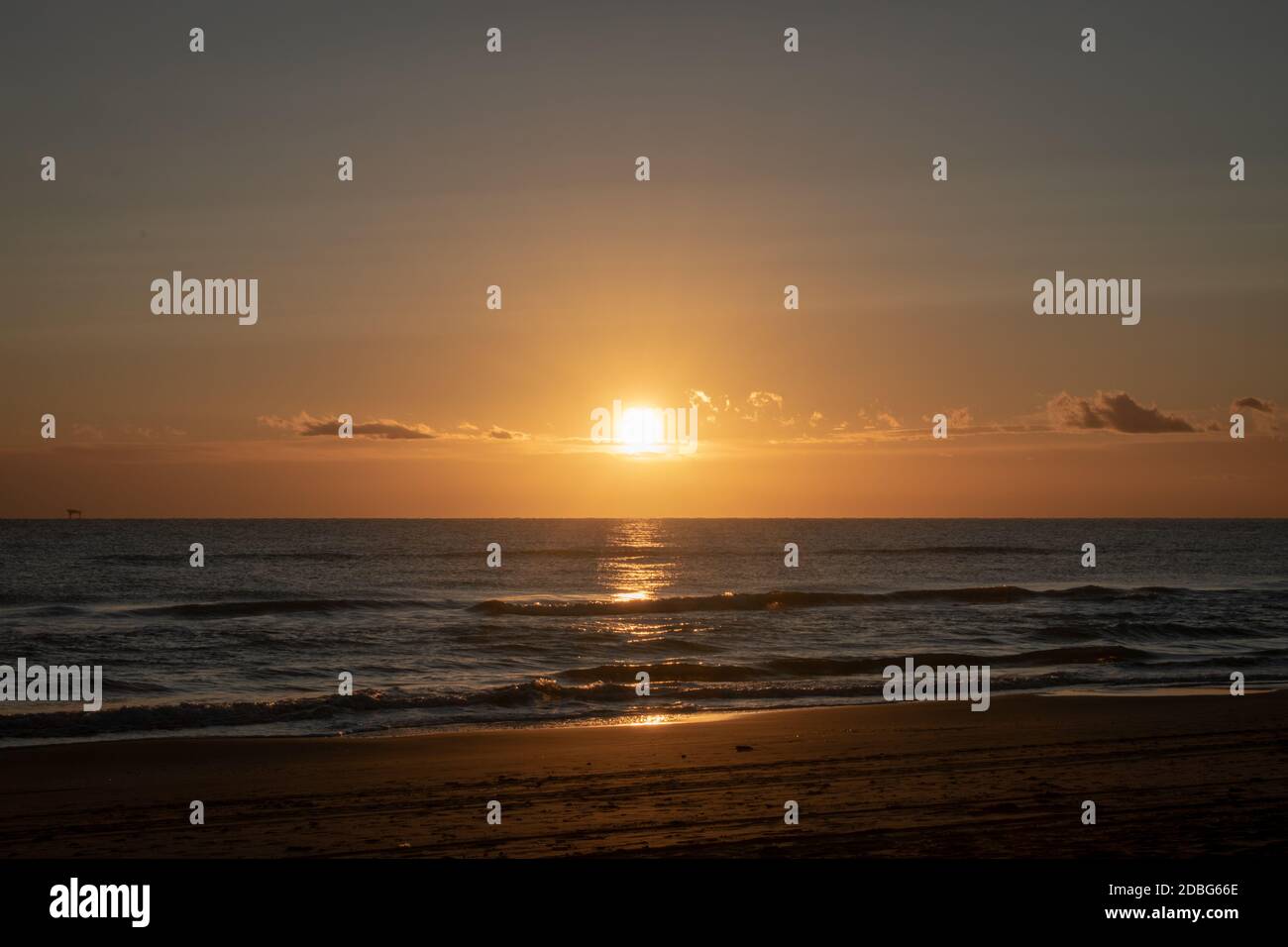 Sonnenuntergang am Strand mit Reflexion und Wellen Stockfoto