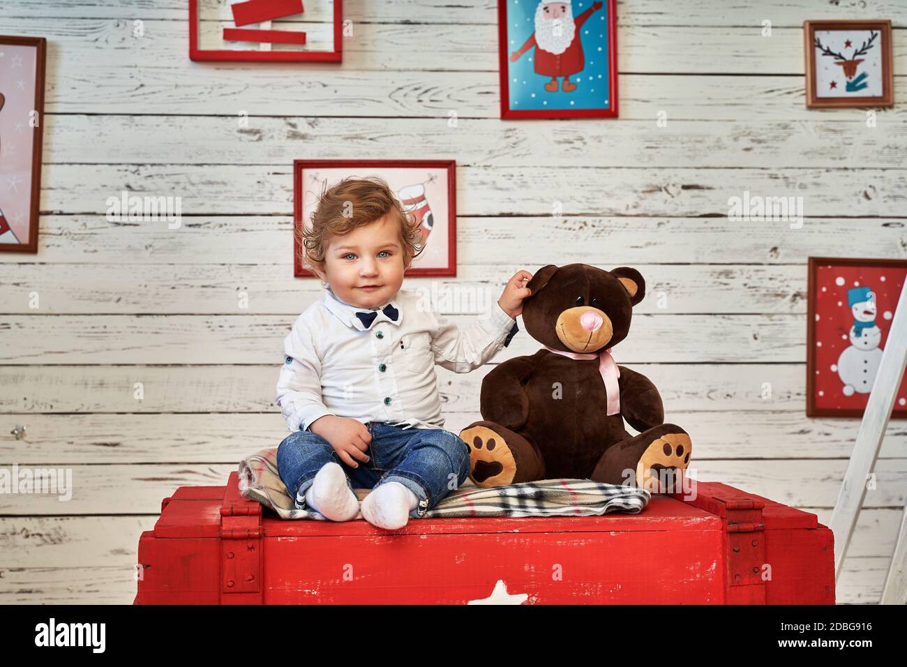 Ein kleiner Junge sitzt auf einer Brust daneben Ein Spielzeug Stockfoto