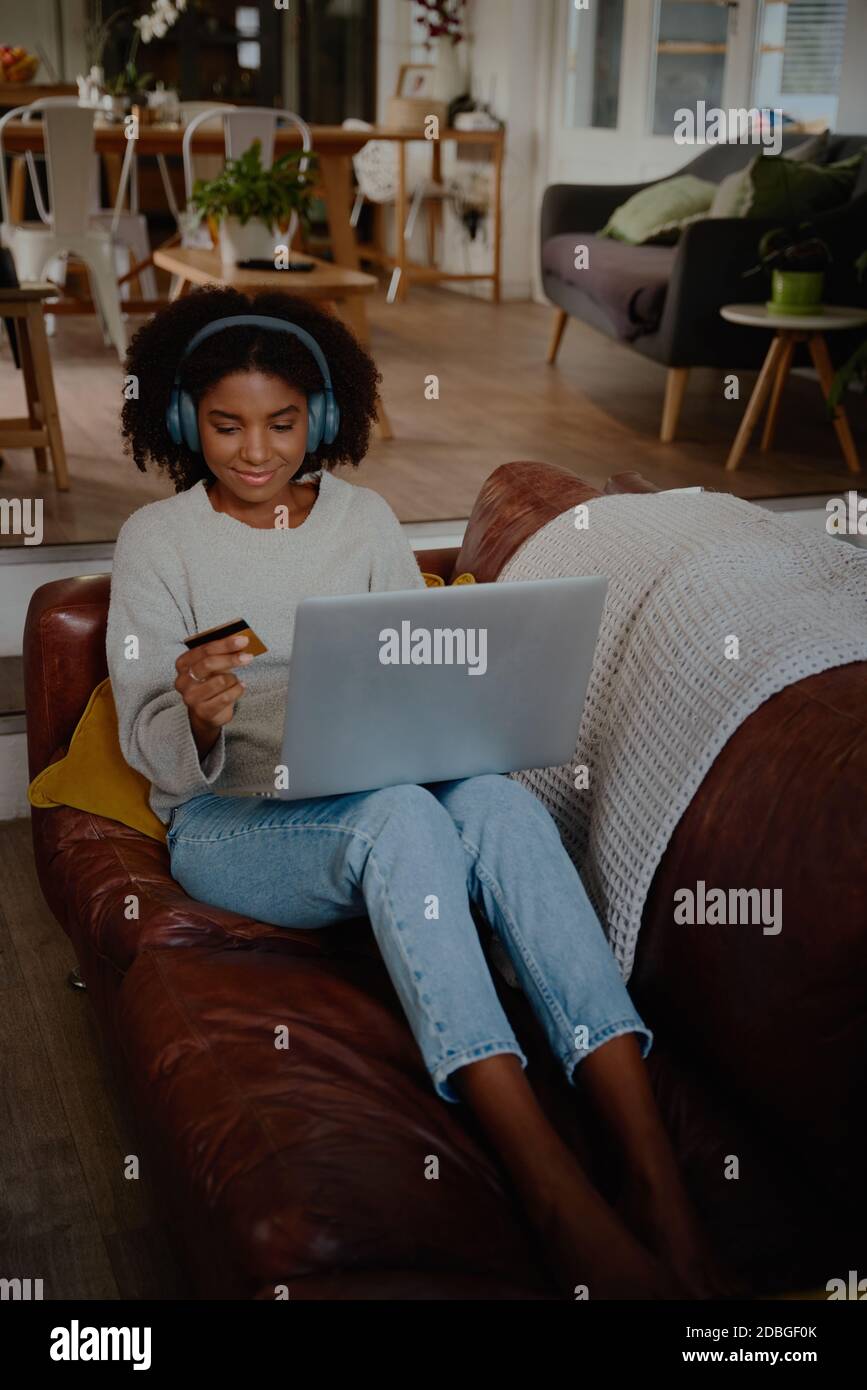 Junge Frau macht eine Online-Zahlung mit Kreditkarte entspannend Zu Hause auf dem Laptop Stockfoto