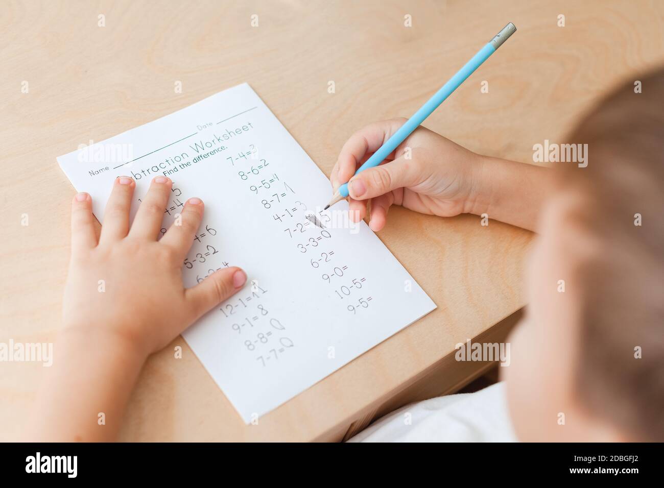 Kinder lösen mathematische Übungen. 7 Jahre alter Junge, der Mathematik-Unterricht macht, sitzt am Schreibtisch in seinem Zimmer. Blick von seinem Rücken, Nahaufnahme Stockfoto