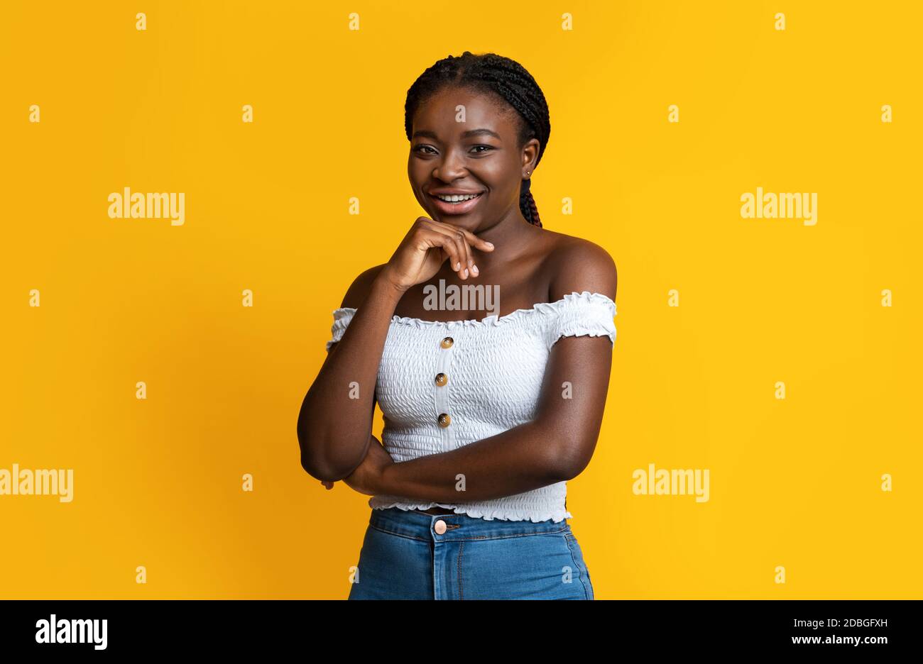Selbstbewusst Attraktive Schwarze Frau Posiert Über Gelben Hintergrund, Lächelnd An Der Kamera Stockfoto