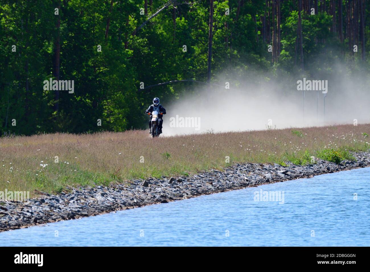 Motorradfahrer mit Staub auf einem Weg Stockfoto