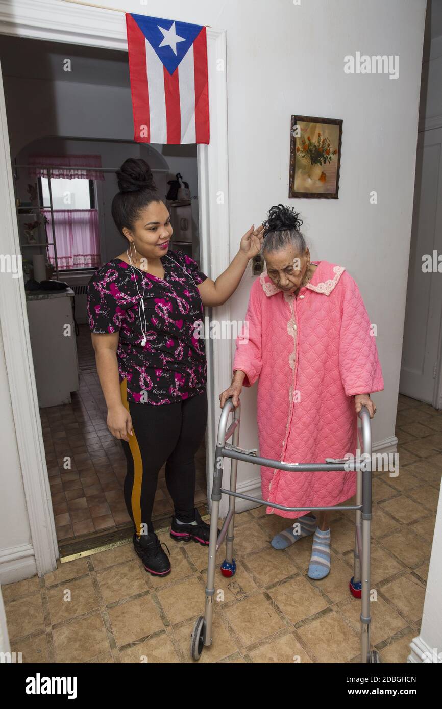 0ne einhundertjährige Frau mit ihrer häuslichen Gesundheitshilfe zu Hause in East Harlem, New York City. Stockfoto
