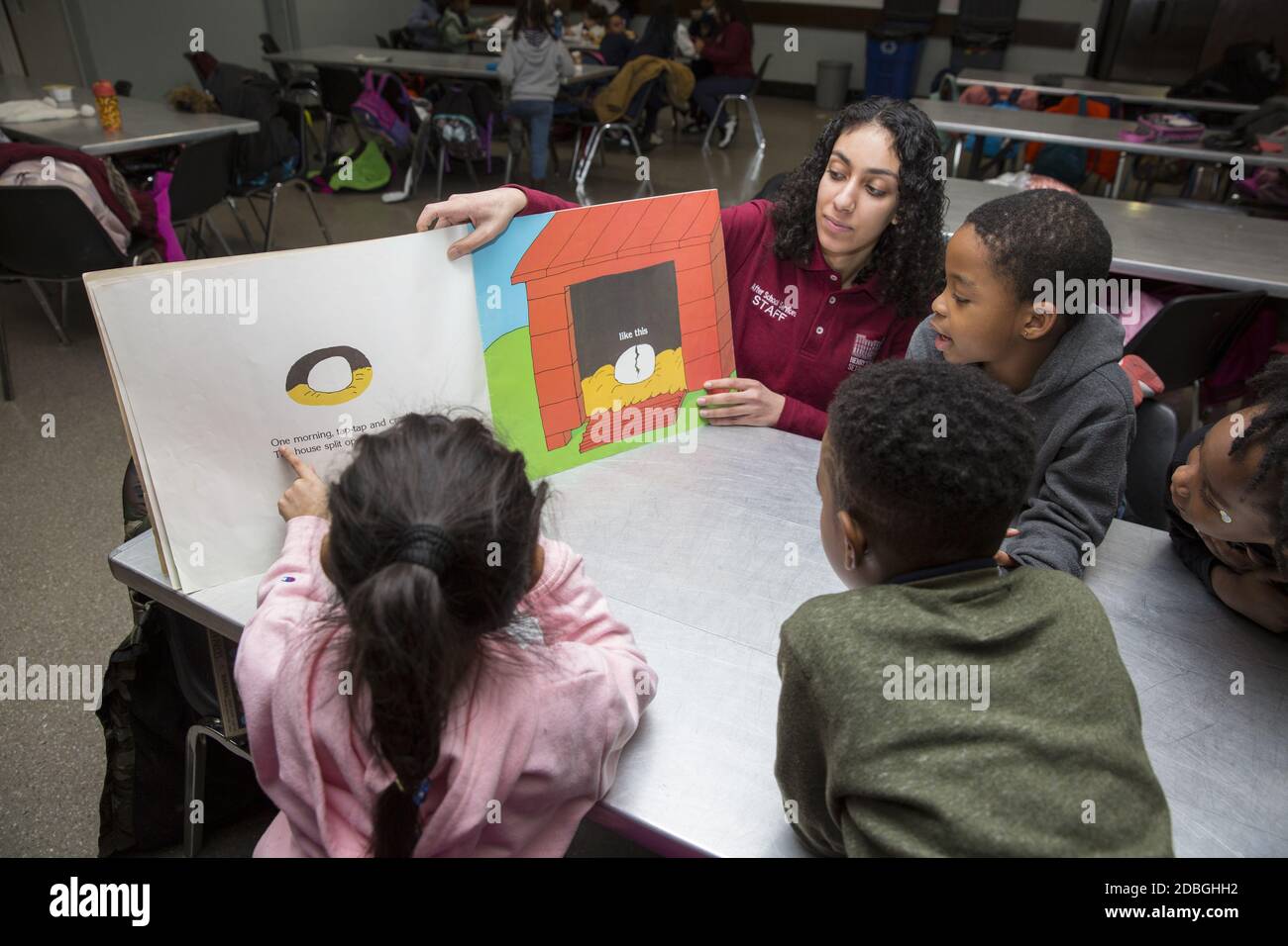 Der Lehrer arbeitet mit Grundschülerinnen und Grundschülerinnen an einem Nachschulprogramm in einem Gemeindezentrum in Manhattan, New York City. Stockfoto