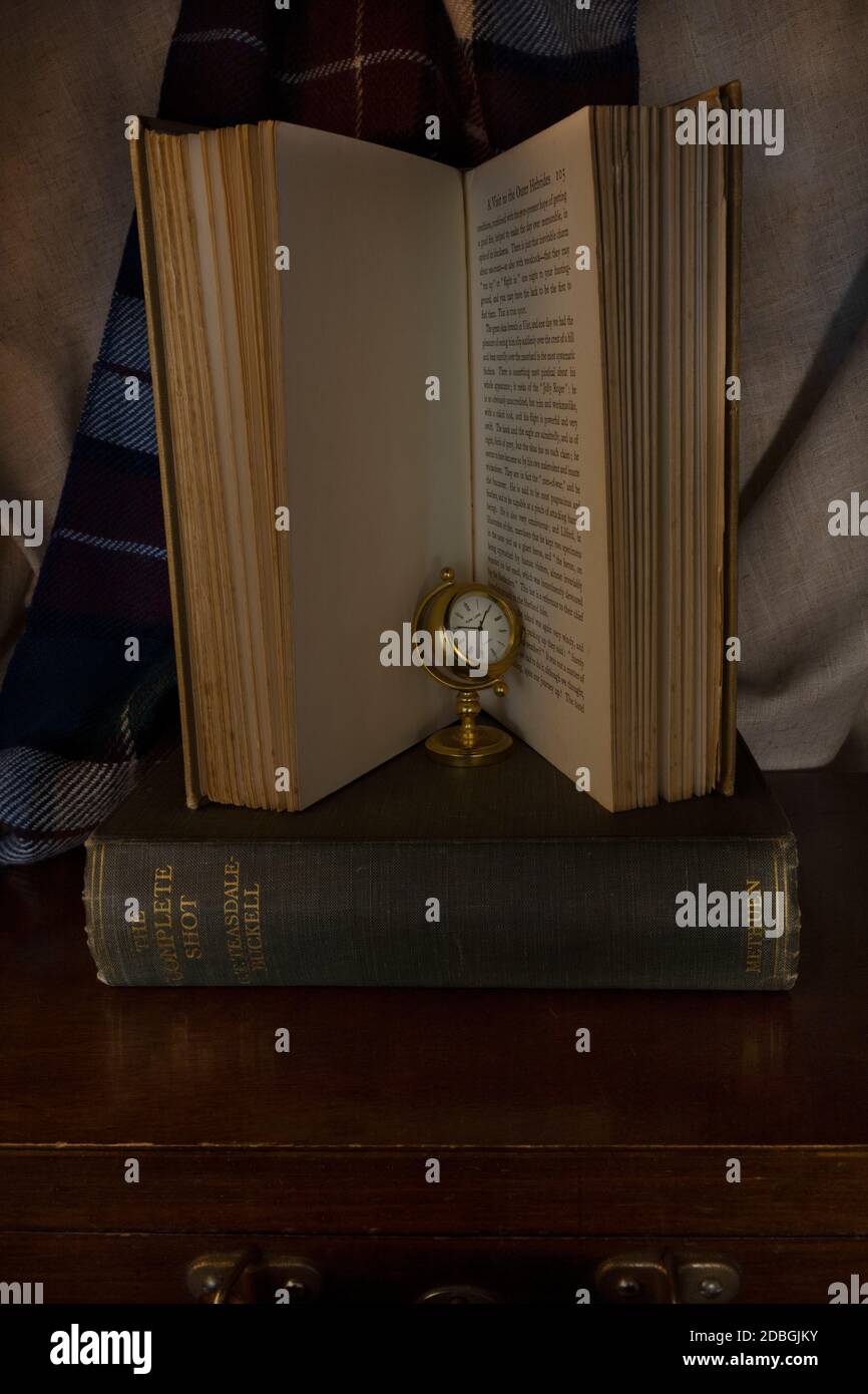 Miniatur-Gold-Uhr in einem offenen Buch auf Grünes Buch auf Holzkiste Stockfoto