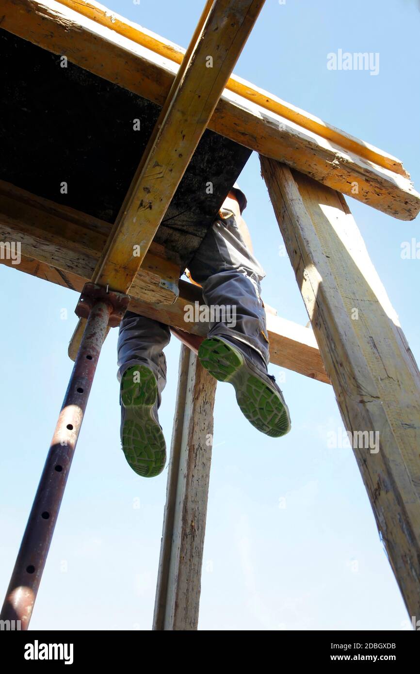 Der Bauarbeiter auf dem Gebäude sitzt in einer Höhe Stockfoto