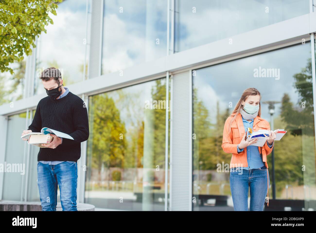 Studenten lernen auf dem Campus halten soziale Distanz, im Hintergrund das Hauptgebäude Stockfoto