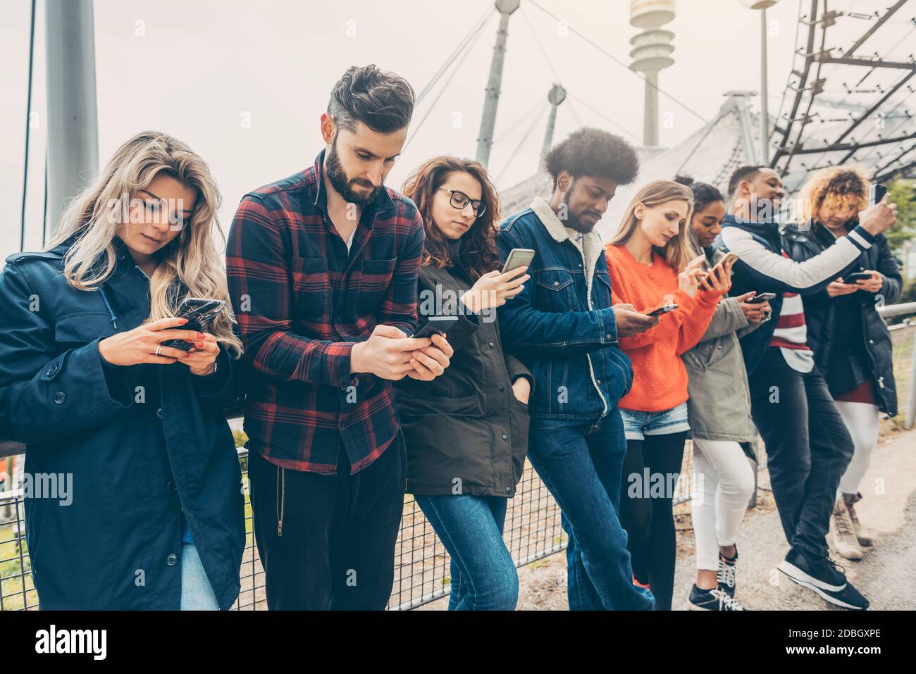 Eine Gruppe junger Menschen, die auf ihr Telefon starren und andere Formen des sozialen Kontakts vermeiden Stockfoto