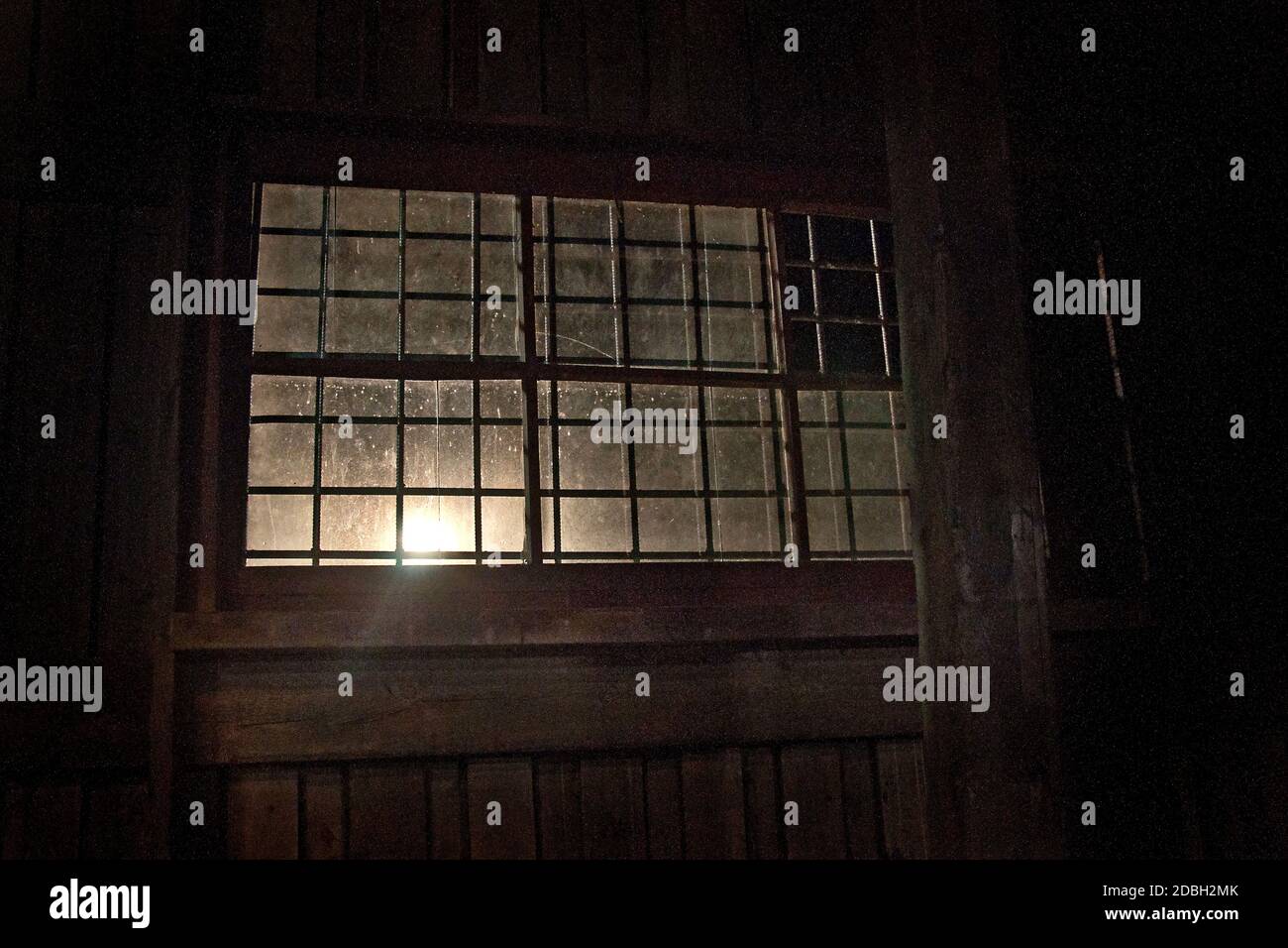 Blick auf das alte Fenster in der Kaserne. Ein Sonnenstrahl durch das Fenster. Ein Bild von Verfall oder Naturkatastrophen Stockfoto