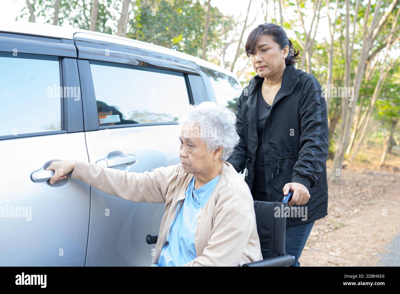 Hilfe und Unterstützung asiatische ältere Frau Patient sitzen auf Rollstuhl vorbereiten bekommen ihr Auto. Stockfoto