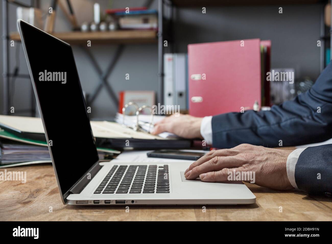 Geschäftsmann, der zu Hause einen Laptop in seinem Büro mit einer Tasse Tee benutzt Stockfoto