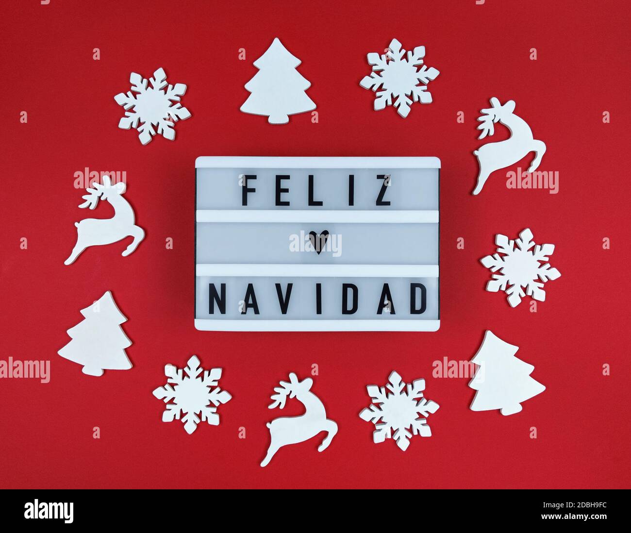 Leuchtkasten mit Feliz Navidad Phrase, Spanisch Frohe Weihnachten auf rotem Hintergrund mit Holzspielzeug. Stockfoto