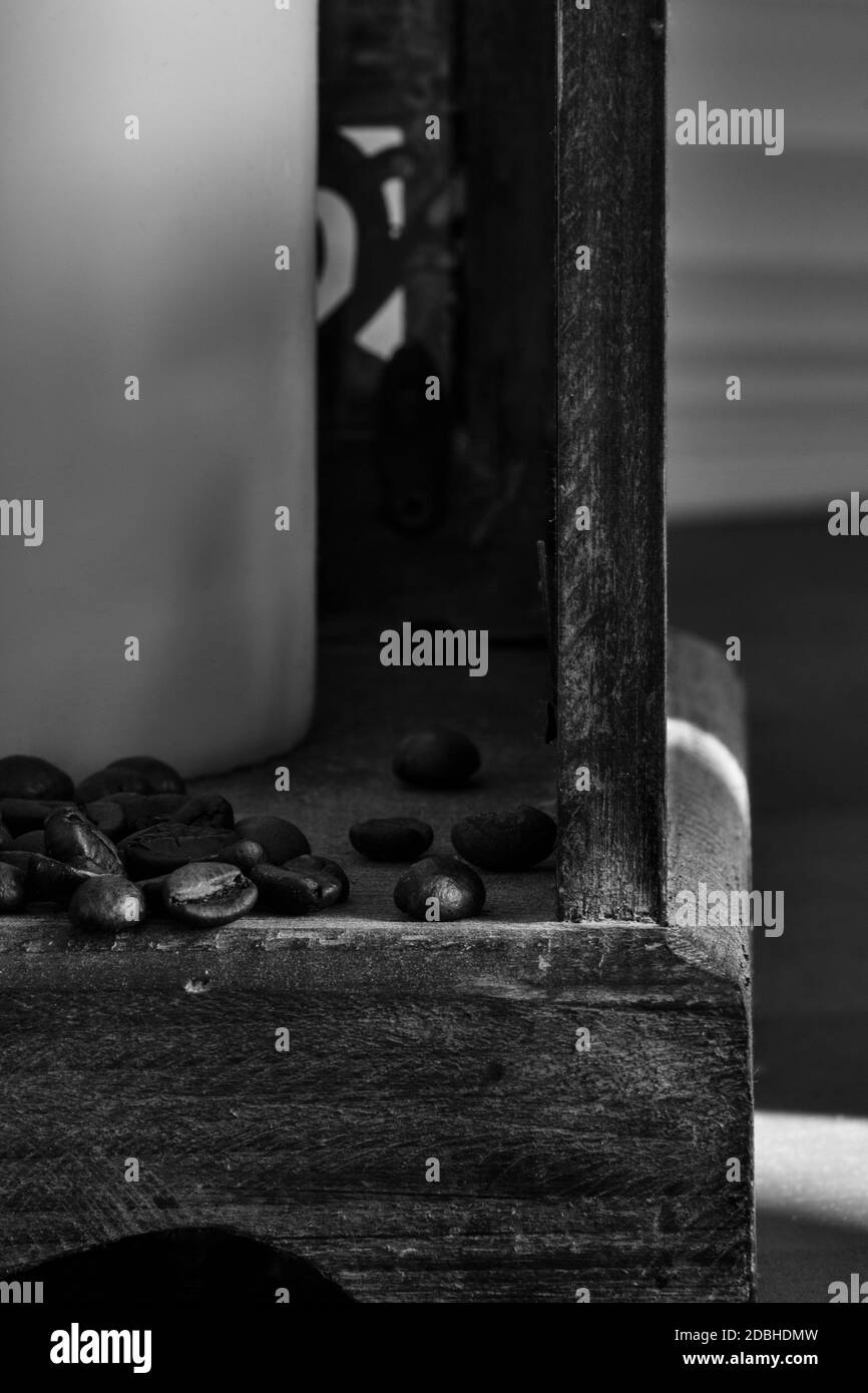 Kaffeebohnen, die aus einer hölzernen Laterne sickern, schwarz und weiß Stockfoto