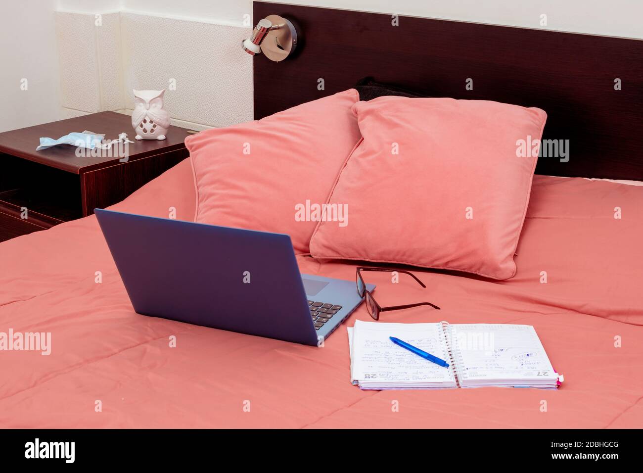 Laptop, Tagebuch und Brille auf einem Bett im Schlafzimmer öffnen. Ich arbeite von zu Hause aus, eine bequeme Form der Kommunikation oder Unterhaltung. Aktuelles Konzept der Arbeit Fr. Stockfoto