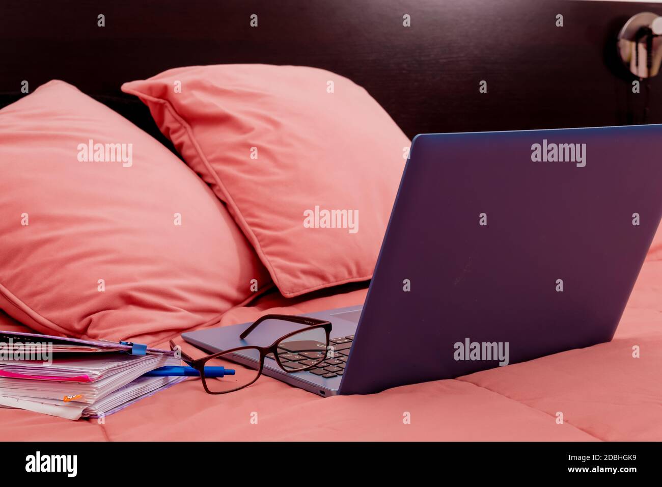 Laptop, Tagebuch und Brille auf einem Bett im Schlafzimmer öffnen. Ich arbeite von zu Hause aus, eine bequeme Form der Kommunikation oder Unterhaltung. Aktuelles Konzept der Arbeit Fr. Stockfoto