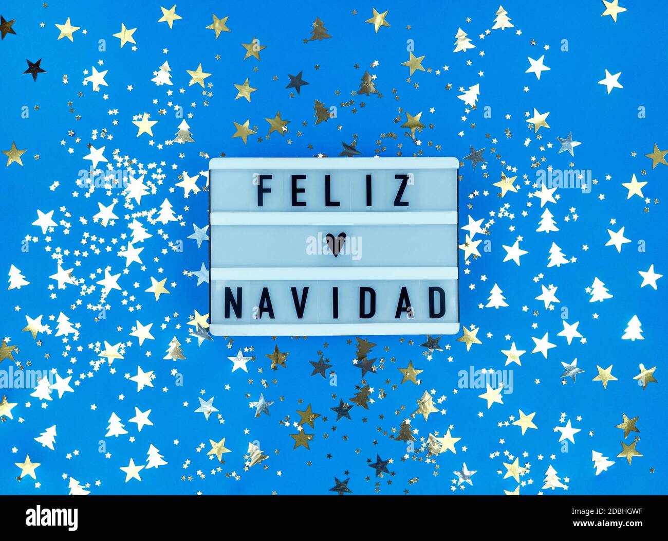 Leuchtkasten mit Feliz Navidad Phrase, Spanisch Frohe Weihnachten auf blauem Hintergrund mit Konfetti. Stockfoto