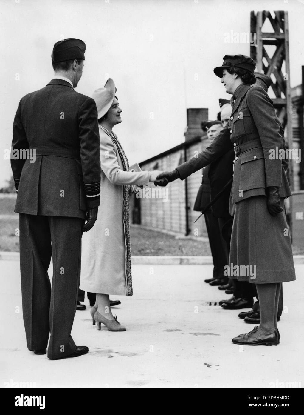 "Queen Elizabeth schüttelt sich die Hände mit Mrs. A.M. Thompson, Stellvertretender Kommandant des ''17th Surrey Womens Auxiliary Territorial Service''' auf der Balloon Barage Display. Neben ihr steht König George VI.' Stockfoto