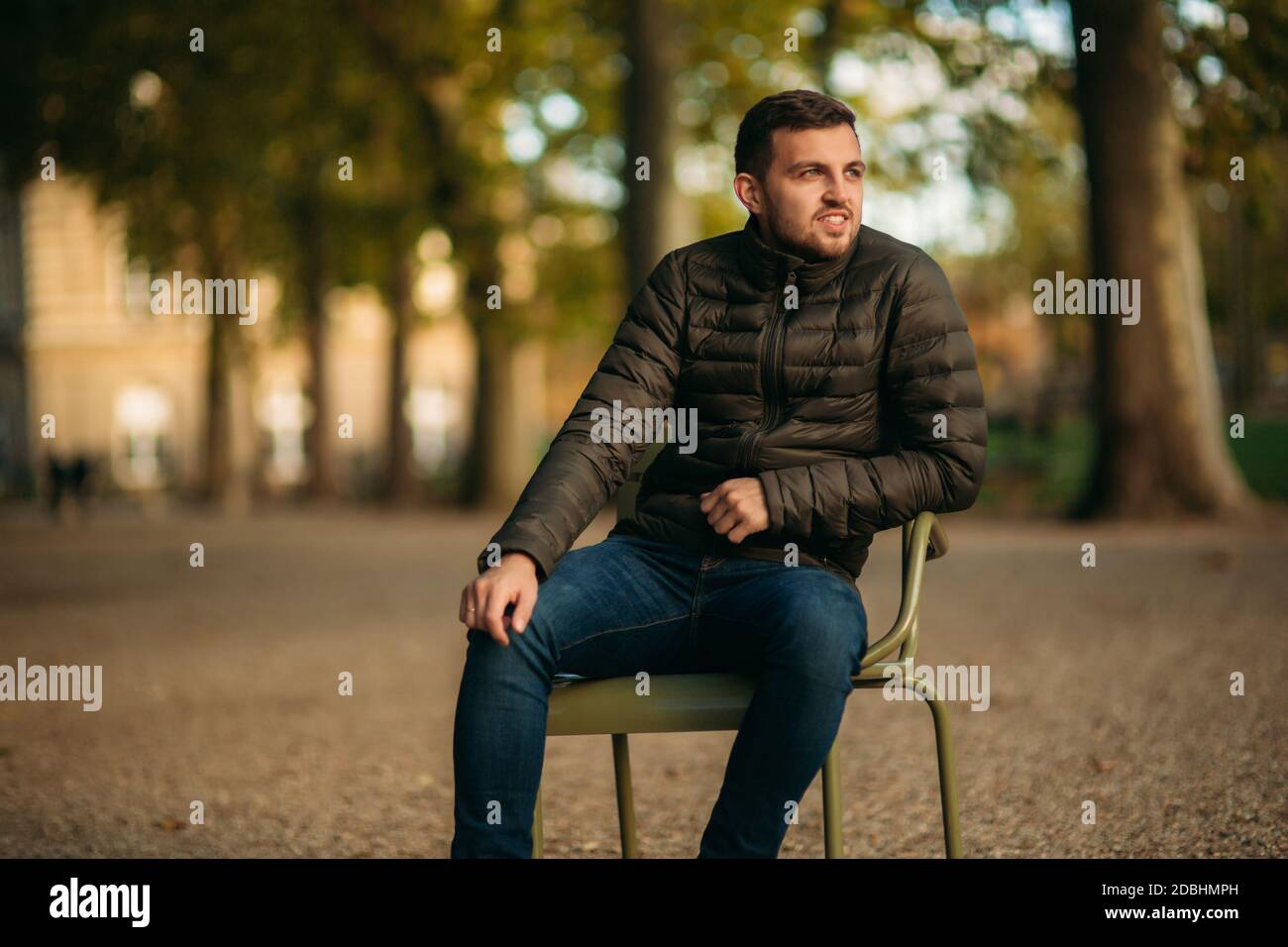 Ein hübscher Mann sitzt mitten im Park Khaki Hocker Stockfoto