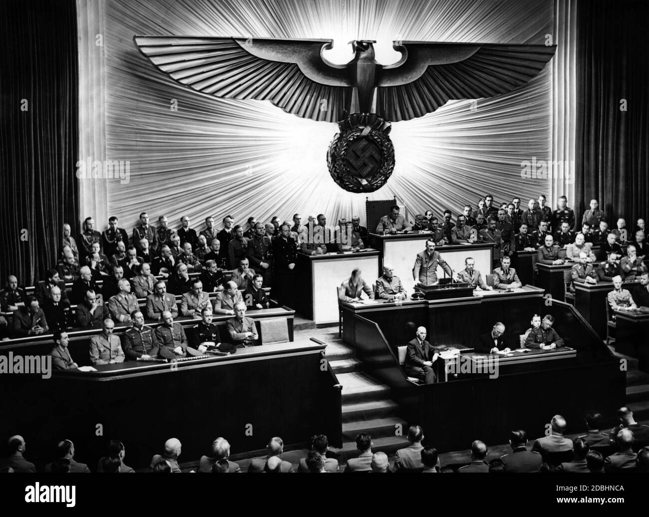 Adolf Hitler während seiner Rede über die Kriegserklärung an die USA. Links von Hitler sind Julius Schaub und Hans Heinrich Lammert, rechts Otto Dietrich und Albert Bormann. Über ihm, Reichstagspräsident Hermann Göring. Neben Hitlers freiem Sitz auf der Regierungsbank sind Joachim von Ribbentrop, Erich Raeder, Walther von Brauchitsch, Wilhelm Keitel, Wilhelm Frick und Joseph Goebbels. Auf der Bank oben, von rechts sitzend: Johann Ludwig Graf Scherin von Krosigk, Walther Funk, Walter Darre, Bernhard Rust, Hanns Kerrl, Hans Frank, Julius Dorpmueller, Arthur Seys Inquart und Fritz Todt. Stockfoto