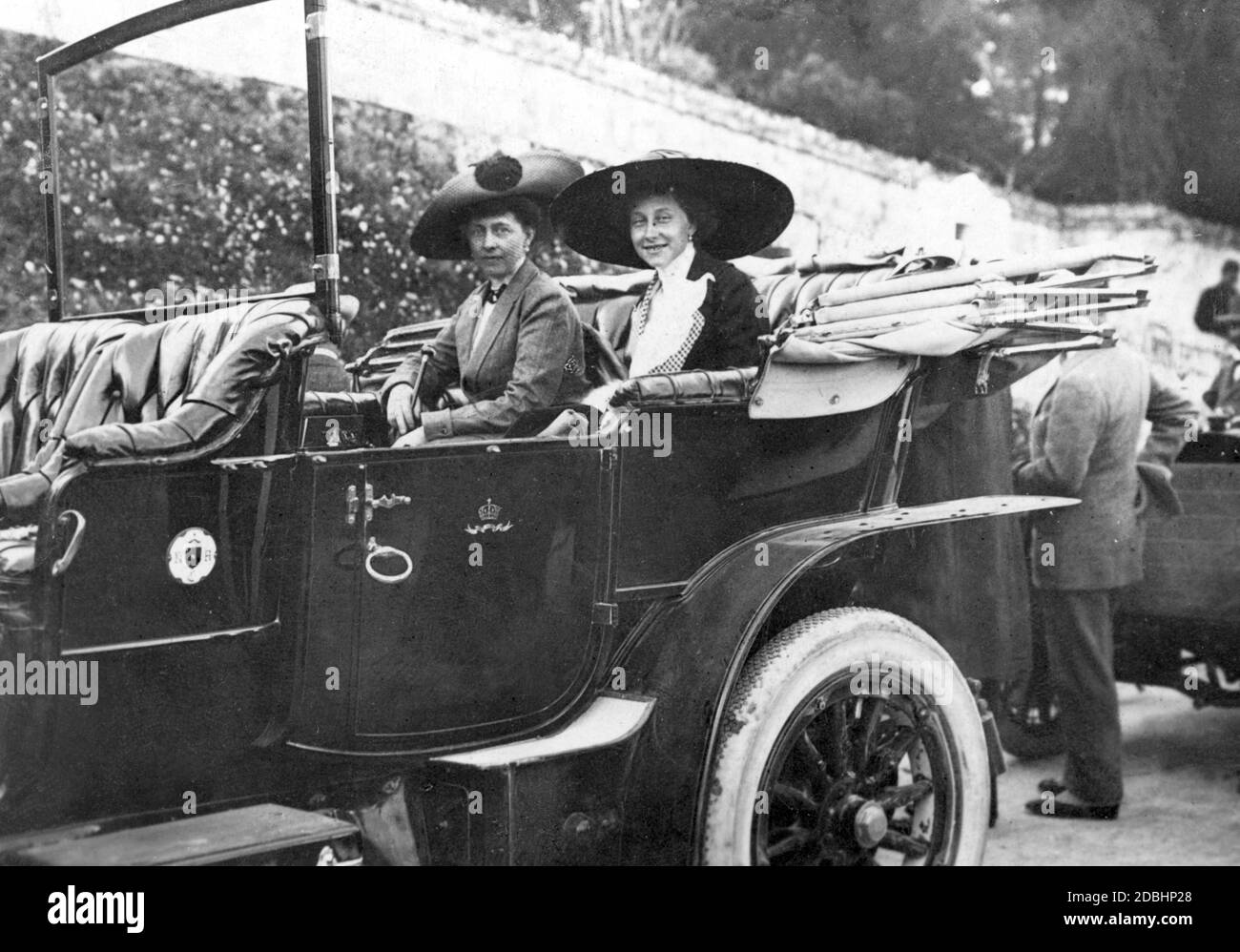 Die kaiserliche Familie reiste 1912 nach Korfu. Auf dem Bild sitzt Prinzessin Victoria Louise von Preußen (rechts) mit ihrer Tante, Kronprinzessin Sophie von Griechenland (links, geb. Preußen, später Königin von Griechenland) kurz vor einem Ausgang im Auto. Das Wappen des Kaiserlichen Automobil-Clubs hängt an der Vordertür des Wagens. Stockfoto