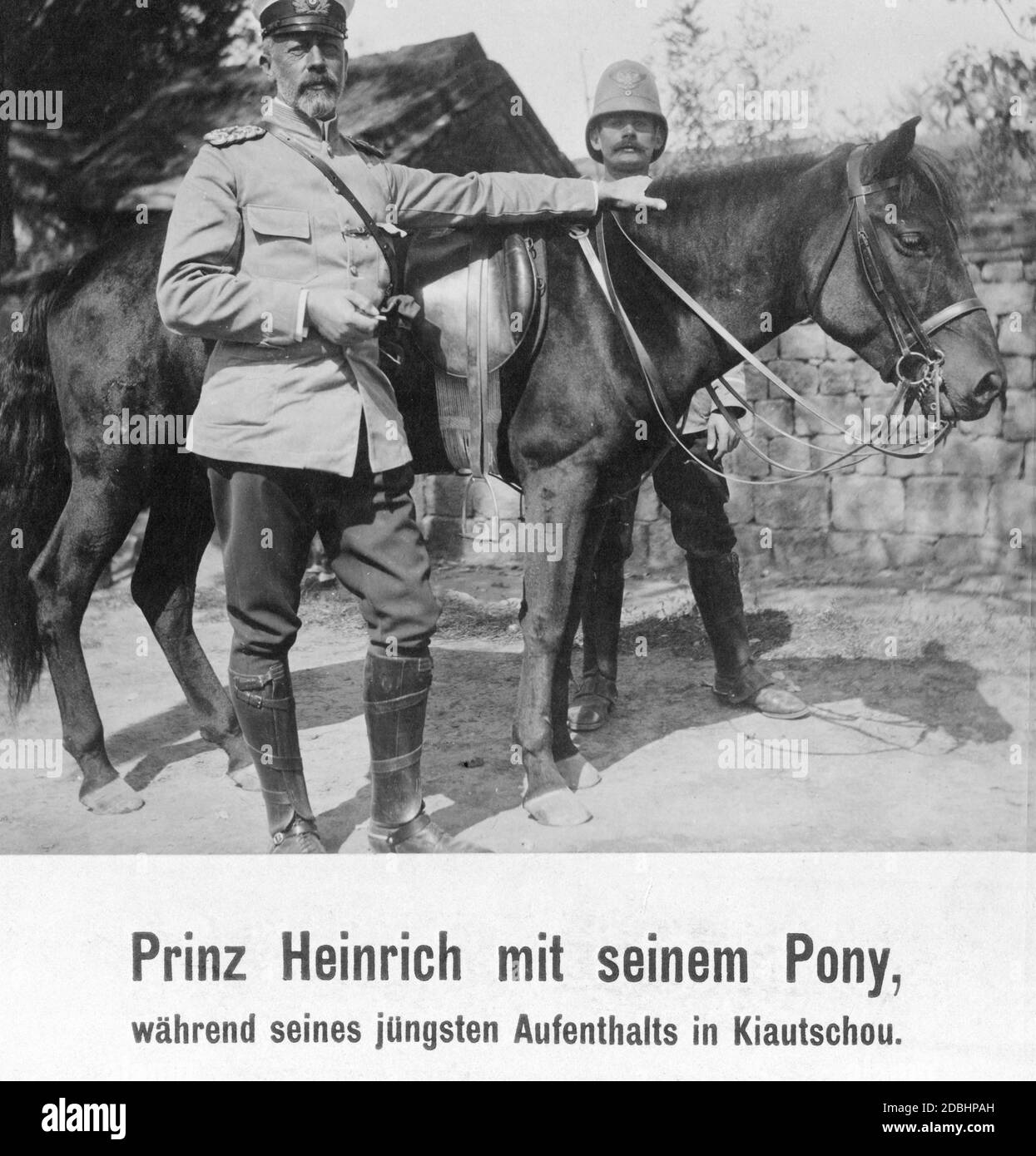 Großadmiral Prinz Heinrich von Preußen (links) war 1912 in die deutsche Kolonie Kiautschou in China gereist. Hier steht er vor seinem Pony und hat eine Zigarette in der Hand. Stockfoto
