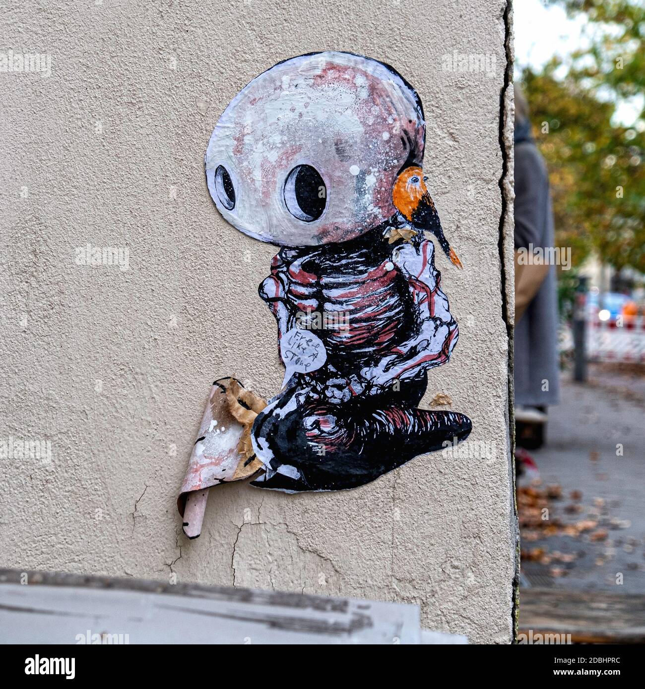 Kleine Straßenkunstwerke an der Gebäudewand. Bild einer Figur mit steinernen Kopf und kleinem Vogel in Mitte, Berlin Stockfoto