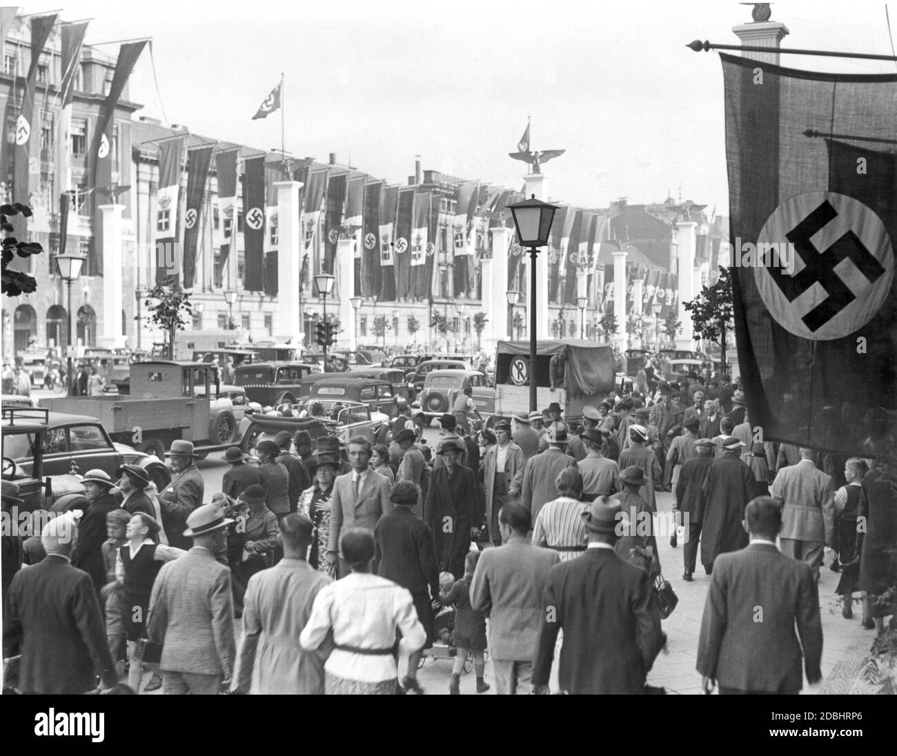Benito Mussolini besuchte Deutschland vom 25. Bis 29. September 1937. Das Bild zeigt Leute, die morgens vor dem Hotel Adlon in der Straße unter den Linden in Berlin auf den späteren Empfang des Duce warten, während der Verkehr noch auf der Straße rollt. Die Straße ist mit zahlreichen Nazi-Symbolen und italienischen Flaggen geschmückt. Stockfoto