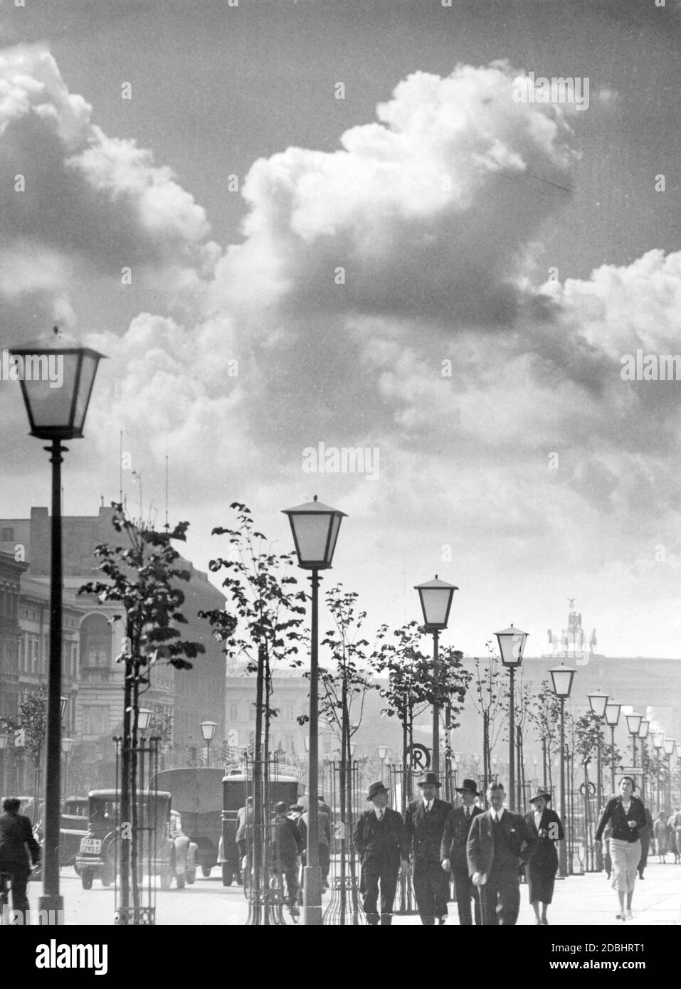 Das Bild aus dem Jahr 1936 zeigt einen Abschnitt des Boulevards unter den Linden in Berlin mit noch jungen Linden zwischen den Straßenlaternen. Im Hintergrund die Quadriga am Brandenburger Tor, links das Hotel Adlon. Stockfoto