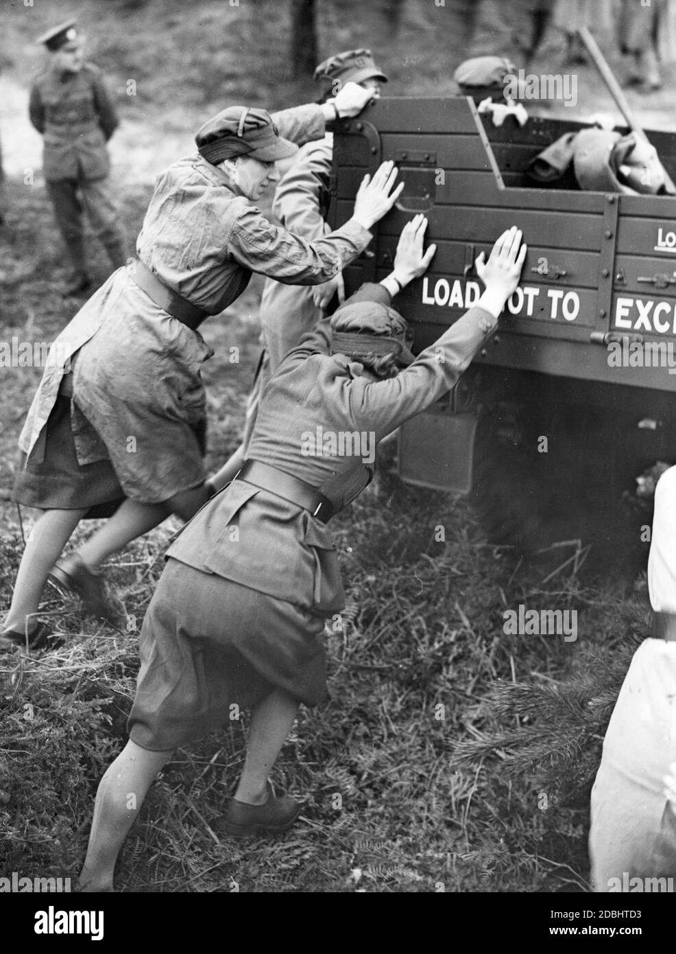 Uniformierte weibliche Mitglieder des Kriegshilfsdienstes schieben einen verklemmten Lastwagen. (Undatierte Aufnahme) Stockfoto