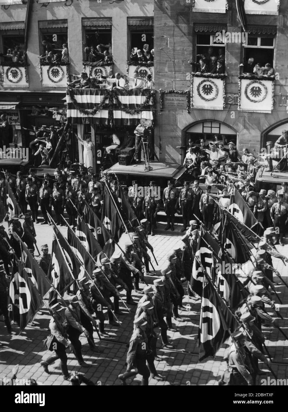 Blick auf einige Formationen der SA und SS, die auf dem NSDAP-Kongress in Nürnberg am festlich geschmückten sogenannten Adolf-Hitler-Platz vorbeimarschieren. Hier vor der ehemaligen Residenz von Willibald Pirckheimer. Stockfoto