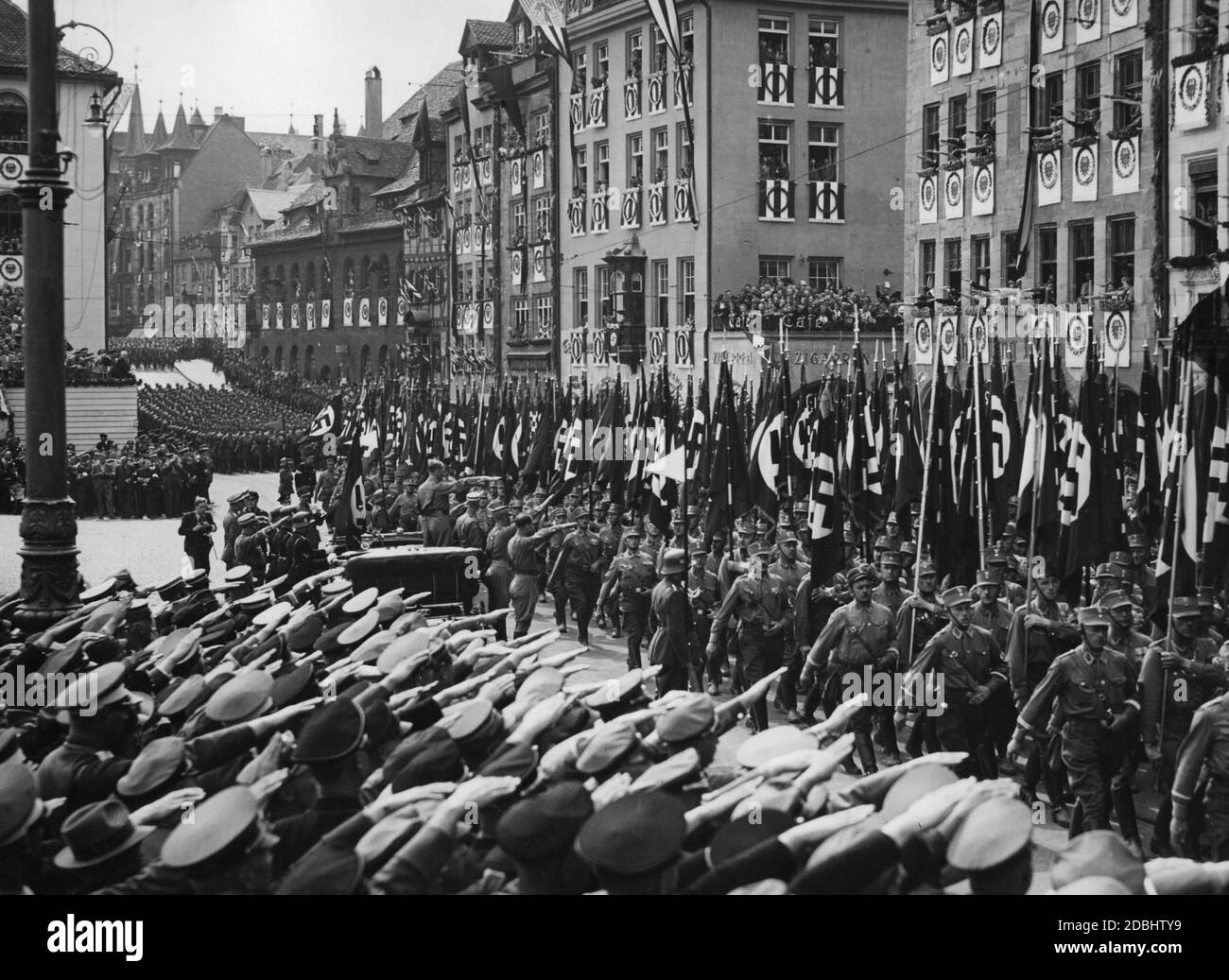 Adolf Hitler in einem Mercedes grüßt die SA-Formationen auf dem festlich geschmückten Adolf-Hitler-Platz in Nürnberg. Stockfoto