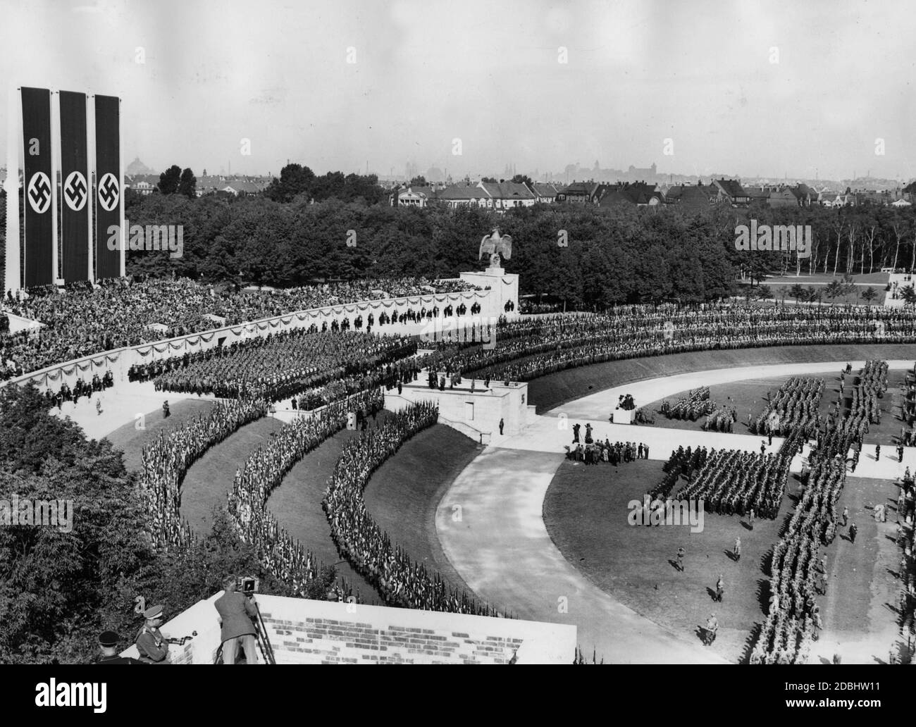 Die Formationen der SA, SS und NSKK Reihen sich in der Luitpoldarena auf dem Gelände der Reichsparteitagsversammlung ein. Im Vordergrund ein Fotograf mit seiner Kamera auf einem Stativ, links das Rostrum. Stockfoto
