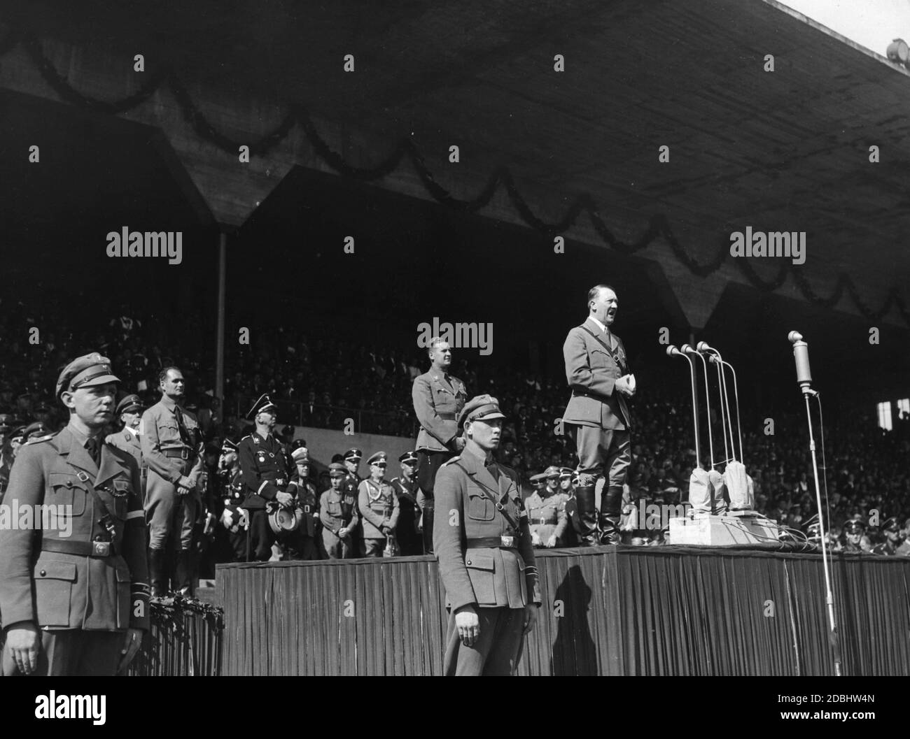 Adolf Hitler hält eine Rede vor den rund 45,000 Mitgliedern der HJ im Stadion der Hitlerjugend. Hinter ihm steht Reichsjugendführer Baldur von Schirach, etwas links Rudolf Hess, hinter ihm Bernhard Rust und rechts Julius Schaub. Hinter ihm Schirach Rudolf Schmundt. Stockfoto
