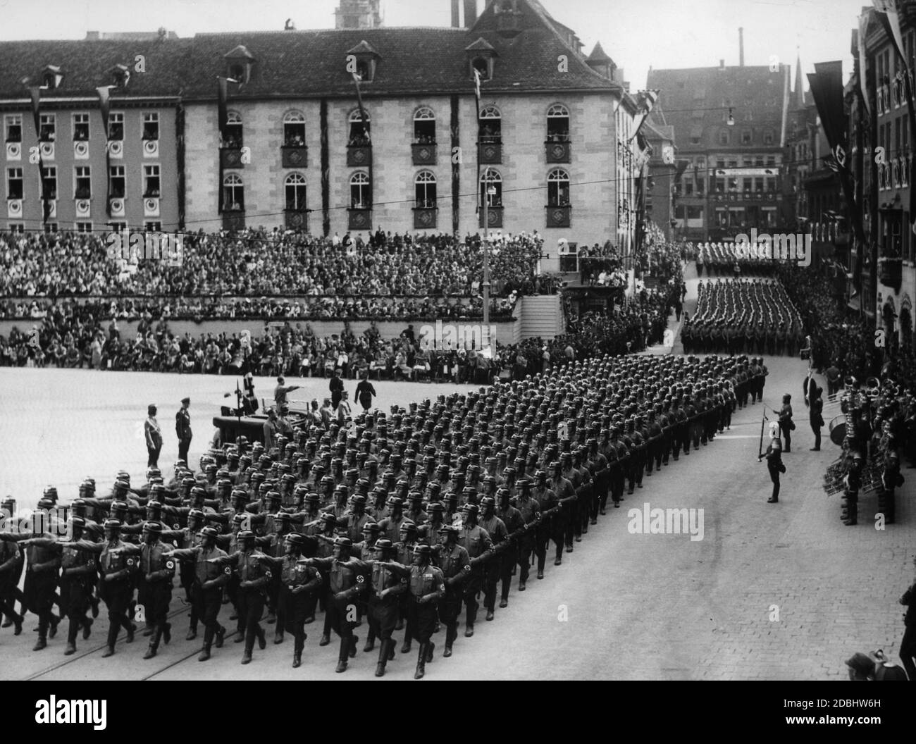 Adolf Hitler (neben ihm Rudolf Hess und Adolf Huehnlein) nimmt in einem Mercedes die Parade der NSKK-Formationen auf Nürnbergs Hauptmarkt, dem sogenannten Adolf-Hitler-Platz, in die Hand. Im Hintergrund die Tribüne. Rechts eine Musikband. Stockfoto