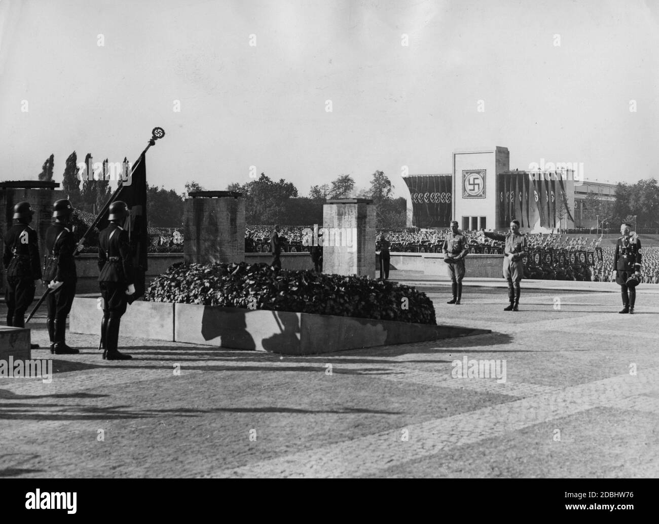 An der Gedenkstätte vor der Halle von Honou in der Luitpoldarena am Tag der SA, SS und NSKK. Von links: Viktor Lutze (Stabschef der SA), Adolf Hitler und Heinrich Himmler (Reichsführer-SS) gedenken der Toten des Bierhaussaales Putsch. Auf der linken Seite sind Männer der SS mit der Blutflagge. Im Hintergrund die Luitpoldhalle. Stockfoto