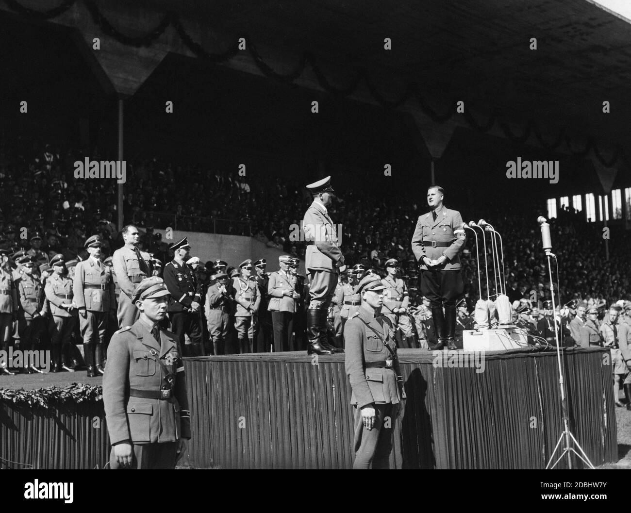 Bei der Parade der HJ im Stadtstadion bittet Baldur von Schirach Adolf Hitler, zu den Massen zu sprechen. Im Hintergrund von links Reichsminister Bernhard Rust und Rudolf Hess, sowie die Adjutanten Julius Schaub und Wilhelm Brückner. Stockfoto