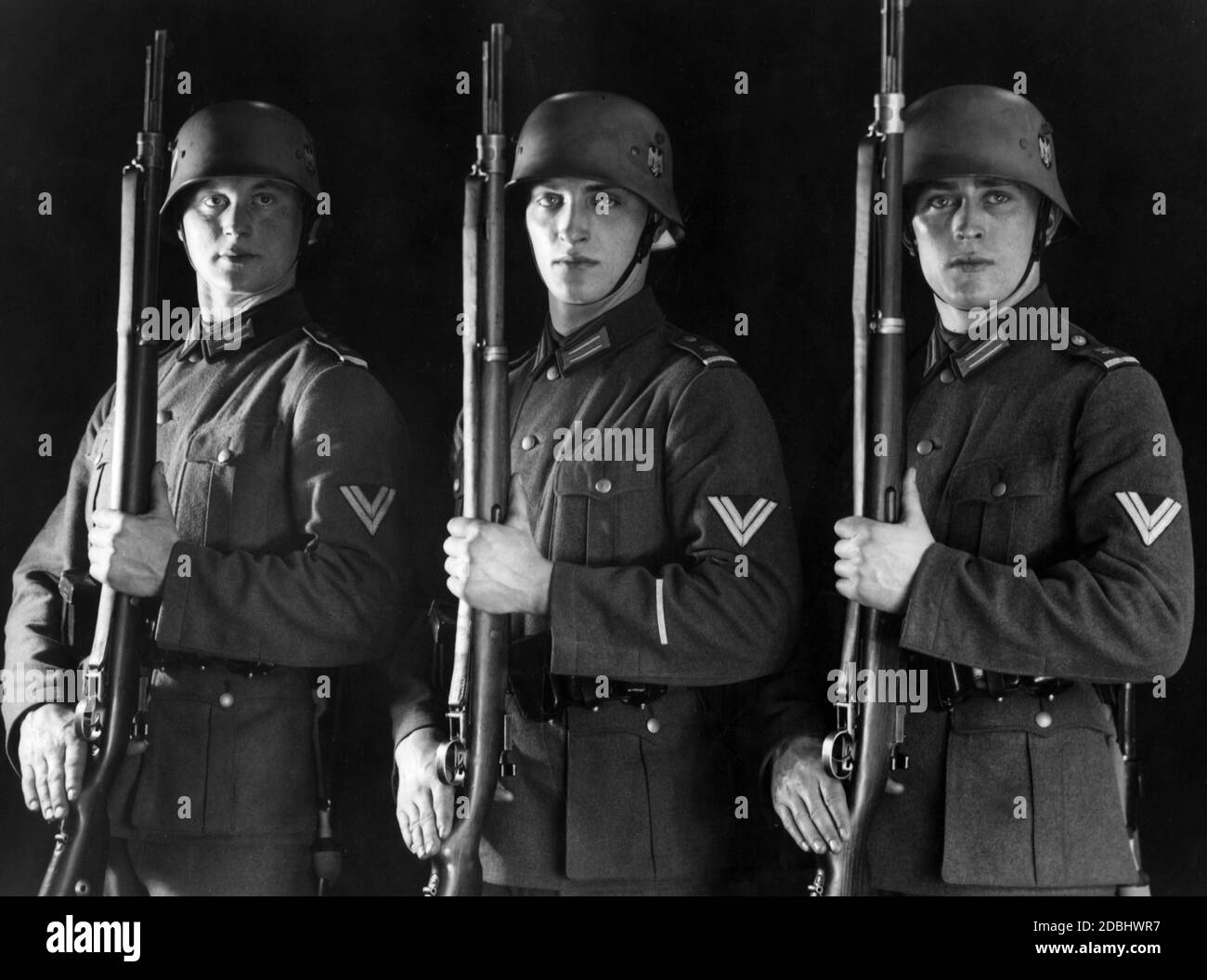 Studiofoto von Soldaten des Berliner Garde-Bataillons in Praesentiergriff. Sie tragen die neue Uniform Feldbluse 36, aber immer noch die Stahlhelm 18 Helme, die bereits mit dem neuen souveränen Insignien der NS-Zeit versehen sind. Die Gewehre sind vom Typ Gewehr 98. Stockfoto